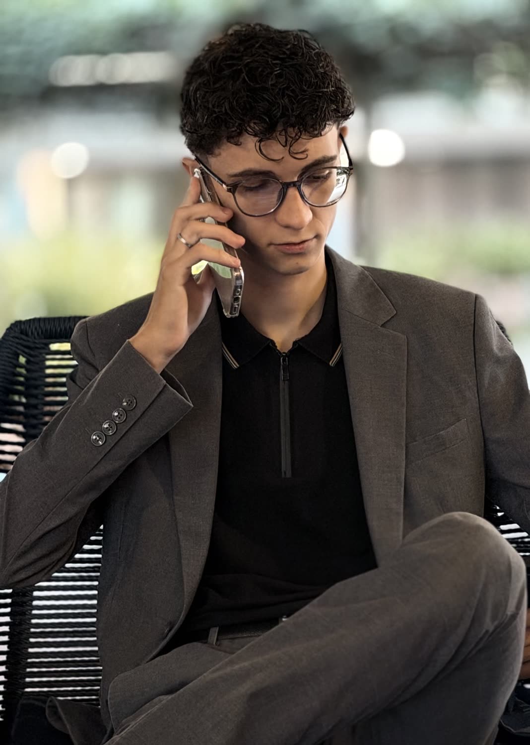 Arthur sentado, de blazer cinza-escuro, falando ao telefone